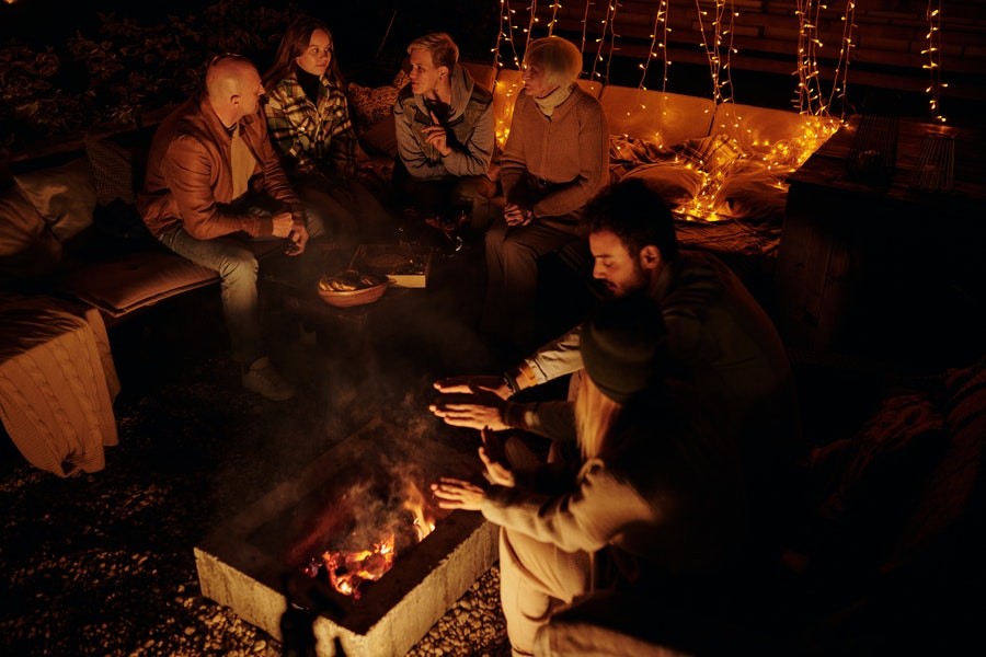 A group of friends gathering to talk around a firepit.
