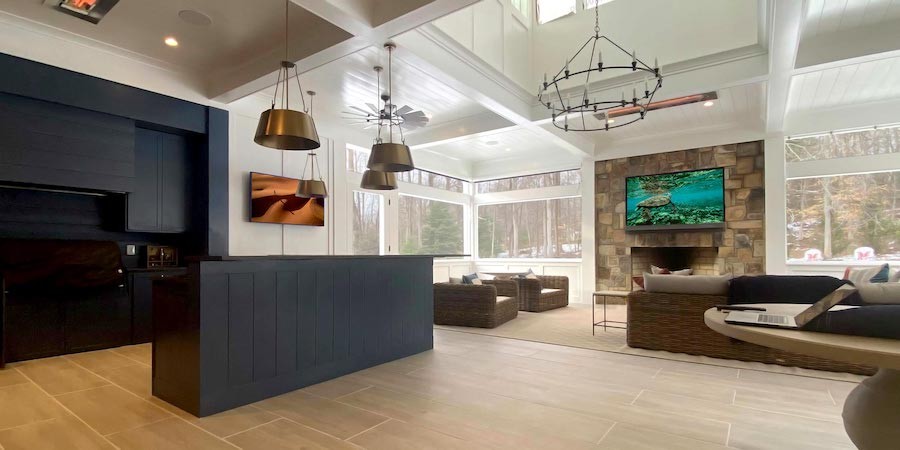 large open concept kitchen and living room with mounted TVs, kitchen island and pendant lighting