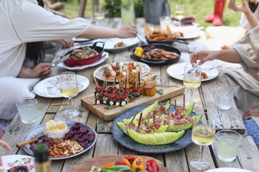 outdoor table with food buffet and people sitting around it