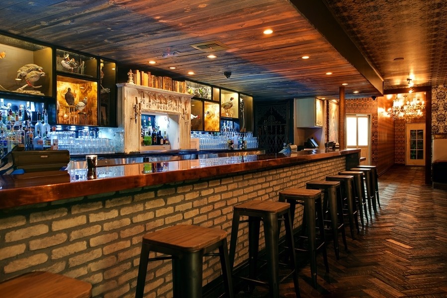 A bar with wooden stools and recessed lights in a wooden ceiling. 